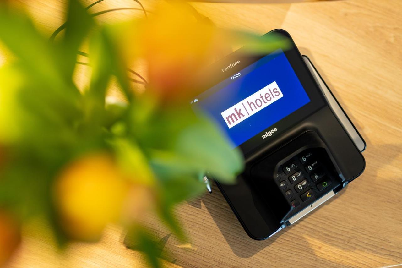 mk hotel tirana Rinas Bagian luar foto A mobile phone with the MK1Hotels logo on the screen